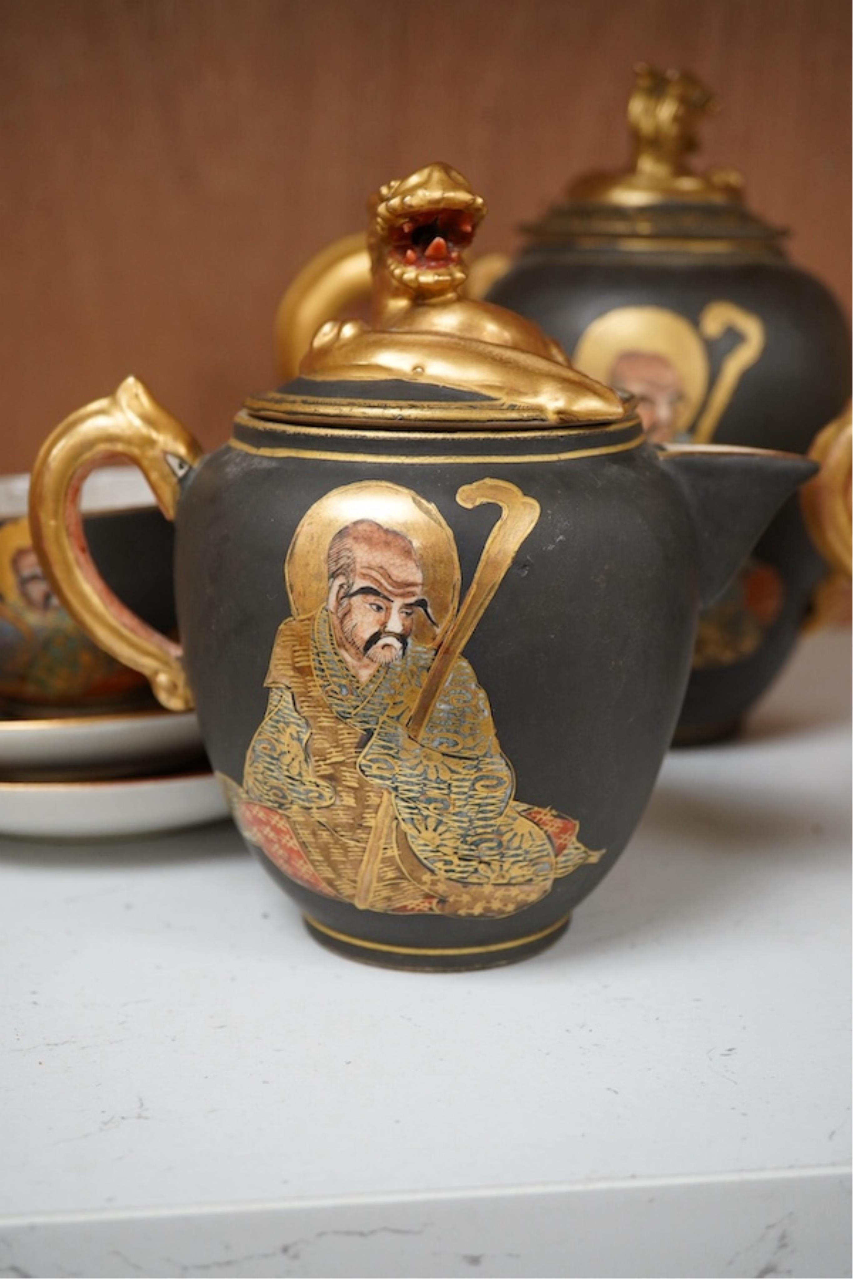 A Japanese Satsuma pottery enamel decorated tea set with Kwannon and rakan, teapot and cover 18cm high. Condition - one cup missing, one cup cracked